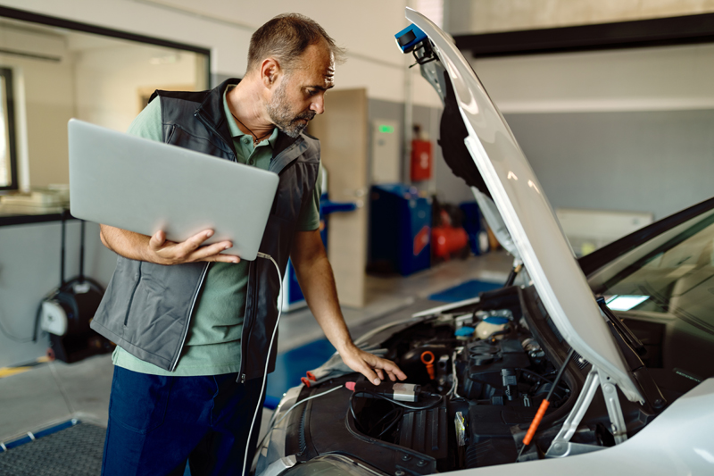 auto-repairman-using-laptop-while-examining-car-engine-in-a-workshop.jpg