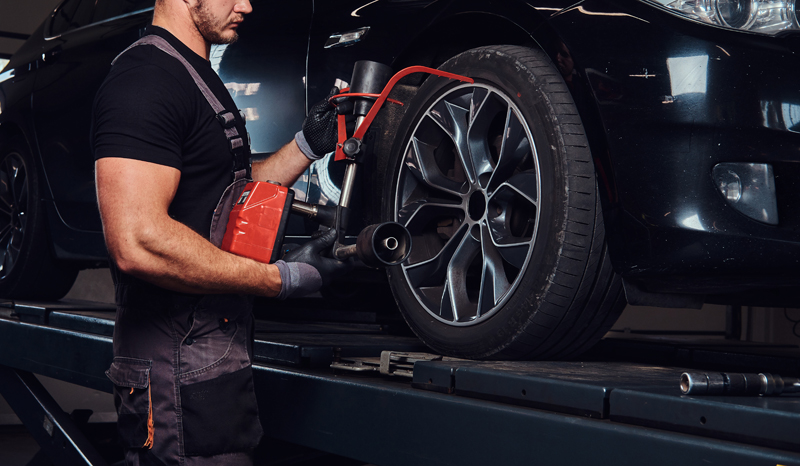 muscular-man-is-fixing-car-s-wheel-with-special-tool-at-auto-service.jpg