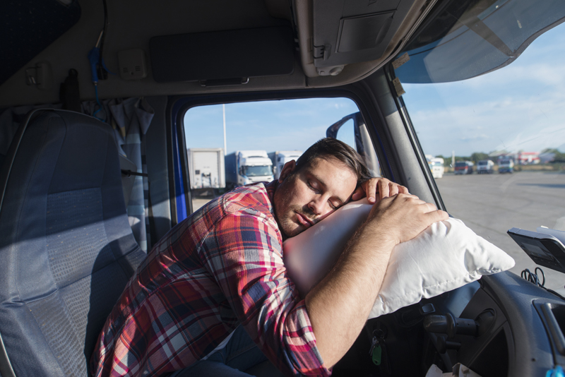 tired-truck-driver-leaned-on-steering-wheel-sleeping-on-his-pillow.jpg