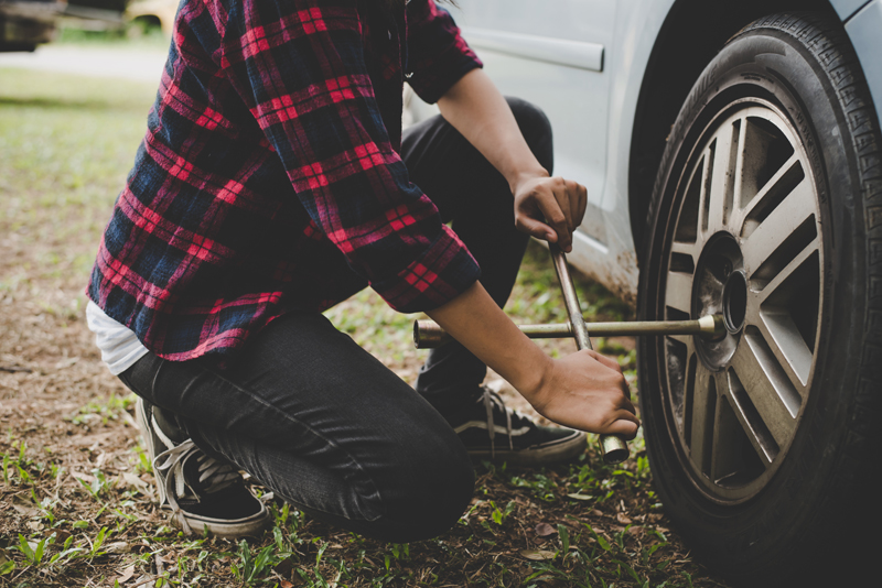 young-hipster-woman-checking-out-a-flat-tyre-on-her-car-try-to-fix.jpg