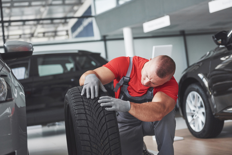 mechanic-holding-a-tire-tire-at-the-repair-garage-replacement-of-winter-and-summer-tires.jpg