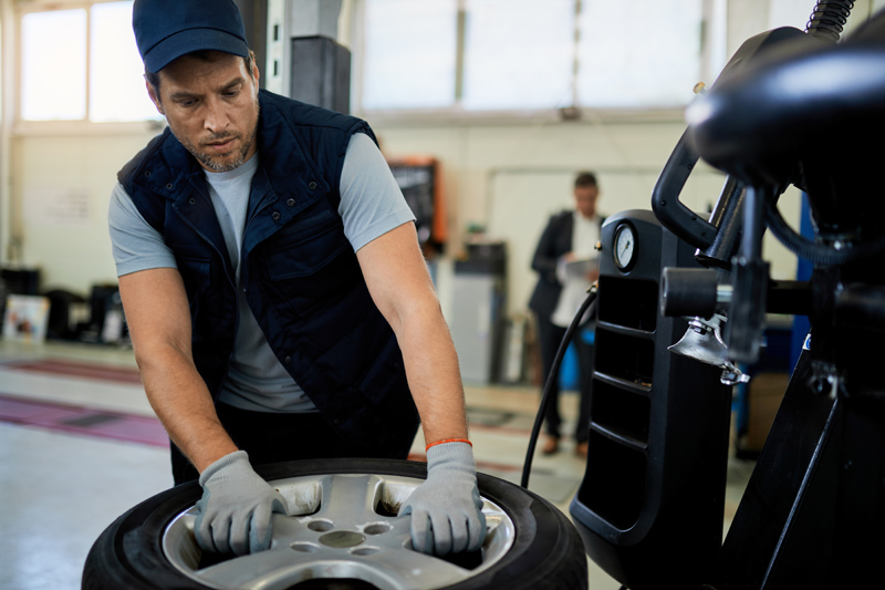 mid-adult-mechanic-working-with-car-tire-in-auto-repair-shop.jpg